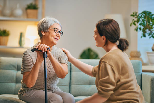 Happy patient and caregiver spending time together. Senior woman holding cane.