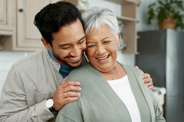 Home, senior mother and son with hug for care, comfort and assurance with bonding together in kitchen. Happy people, elderly mom and man with embrace for mothers day, support and expression of love.