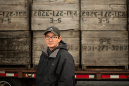 A man standing in front of a truck full of pallets