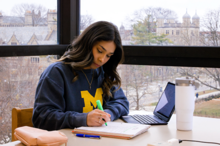 A student highlights their notes while studying at a talbe in the Shapiro Undergraduate Library.
